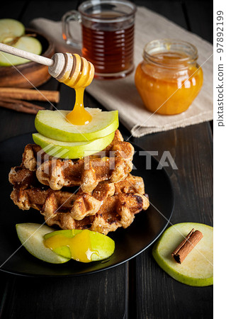 Traditional Belgian waffles topped with sliced green apple and honey Traditional Belgian waffles topped with sliced green apple and honey 97892199