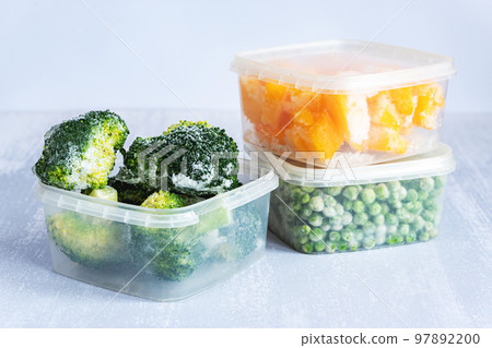 Frozen vegetables. Frozen broccoli, peas and pumpkin in plastic boxes on grey table Frozen vegetables. Frozen broccoli, peas and pumpkin in plastic boxes on grey table 97892200