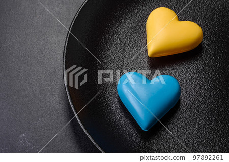 Chocolate hearts in the colors of the Ukrainian flag on a black ceramic plate Chocolate hearts in the colors of the Ukrainian flag on a black ceramic plate 97892261