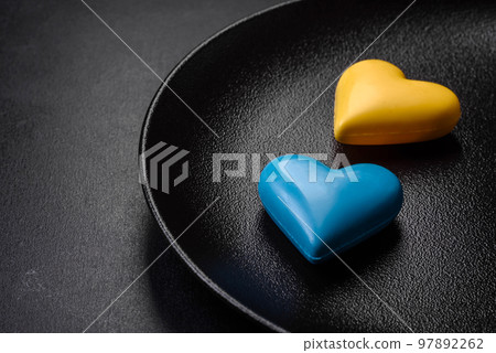 Chocolate hearts in the colors of the Ukrainian flag on a black ceramic plate Chocolate hearts in the colors of the Ukrainian flag on a black ceramic plate 97892262