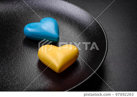 Chocolate hearts in the colors of the Ukrainian flag on a black ceramic plate Chocolate hearts in the colors of the Ukrainian flag on a black ceramic plate 97892263