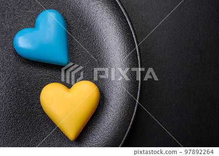 Chocolate hearts in the colors of the Ukrainian flag on a black ceramic plate Chocolate hearts in the colors of the Ukrainian flag on a black ceramic plate 97892264