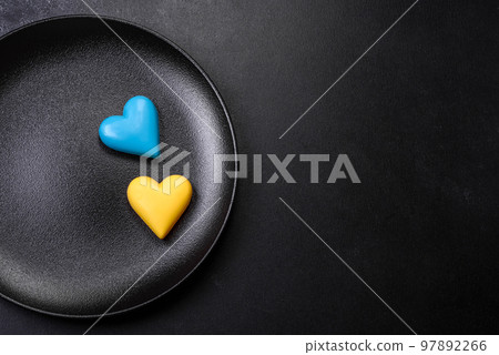 Chocolate hearts in the colors of the Ukrainian flag on a black ceramic plate Chocolate hearts in the colors of the Ukrainian flag on a black ceramic plate 97892266