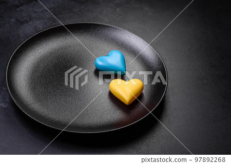 Chocolate hearts in the colors of the Ukrainian flag on a black ceramic plate Chocolate hearts in the colors of the Ukrainian flag on a black ceramic plate 97892268