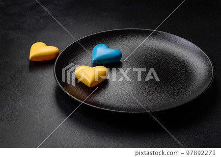Chocolate hearts in the colors of the Ukrainian flag on a black ceramic plate Chocolate hearts in the colors of the Ukrainian flag on a black ceramic plate 97892271