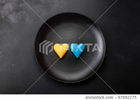 Chocolate hearts in the colors of the Ukrainian flag on a black ceramic plate 97892275