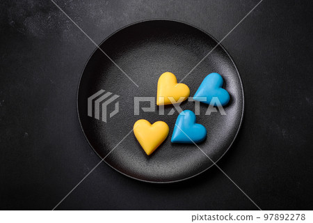 Chocolate hearts in the colors of the Ukrainian flag on a black ceramic plate Chocolate hearts in the colors of the Ukrainian flag on a black ceramic plate 97892278