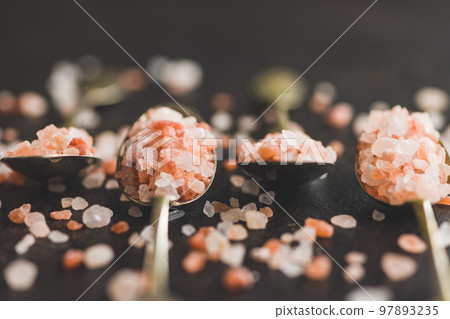 Pink himalayan salt in spoon on black table. Pink himalayan salt in spoon on black table. 97893235