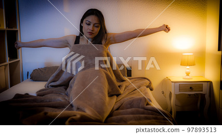 Young Asian woman wakes up while she lies in bed 97893513