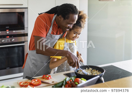 Loving Black Dad And Preteen Female Child Cooking Together In Kitchen Loving Black Dad And Preteen Female Child Cooking Together In Kitchen 97894376