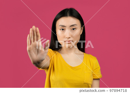 Young japanese lady gesturing STOP, showing rejection gesture, expressing her negative attitude, pink background Young japanese lady gesturing STOP, showing rejection gesture, expressing her negative attitude, pink background 97894718