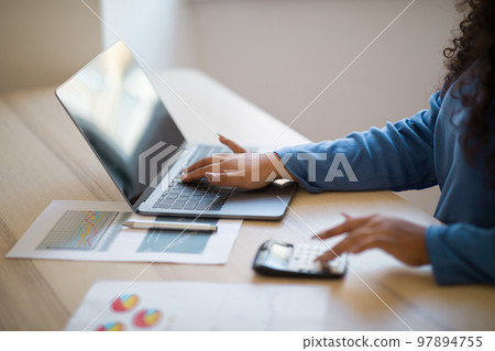 Close up focus on female hands making calculations on laptop Close up focus on female hands making calculations on laptop 97894755