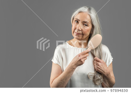 Serious senior caucasian female combing her Stock Photo