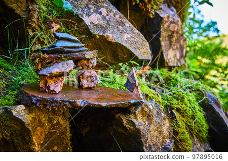 Detail of tiny stone stacks cairn against wall of lichen rocks and moss patches Detail of tiny stone stacks cairn against wall of lichen rocks and moss patches 97895016