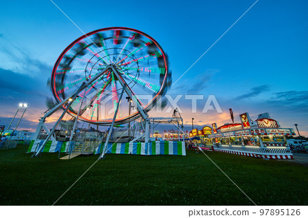 Blurred ferris wheel at American summer county fair during dusk Blurred ferris wheel at American summer county fair during dusk 97895126