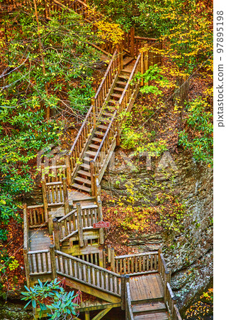 Boardwalk staircase leads up through cliffs with fall leaves and foliage around 97895198