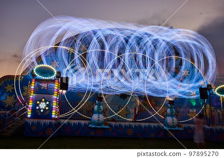 County fair carnival ride with circle light patterns blurred County fair carnival ride with circle light patterns blurred 97895270