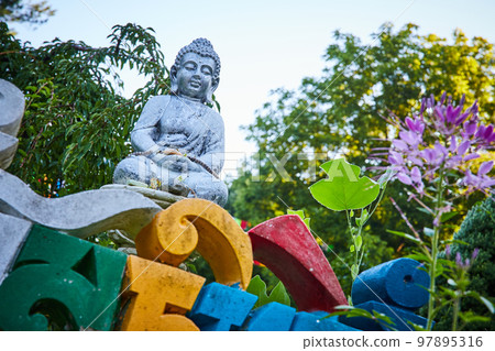 Colorful lettering and small stone Buddha statue at Tibetan Mongolian Buddhist shrine 97895316