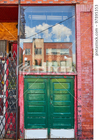 Alley large double green doors with glass display above along red brick wall 97895353