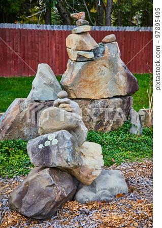 Backyard boulders stacked on top of each other in zen cairn style with wood fence 97895495