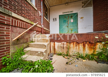 Abandoned building back shipping receiving entrance with brick, rust, and cement steps 97895621