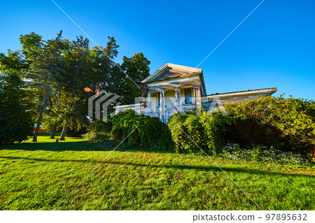 Abandoned old white townhouse home with pillars on front 97895632