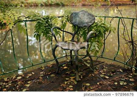 Vintage forged chair near the pond in autumn Vintage forged chair near the pond in autumn 97896676