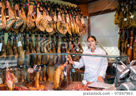 Woman shop assistant demonstrating sorts of meat in butcher shop 97897963