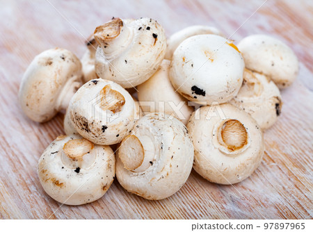 Raw white champignons on wooden surfacen in kitchen 97897965