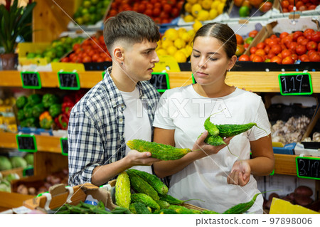 Serious young couple selecting fresh Green Karela at hypermarket Serious young couple selecting fresh Green Karela at hypermarket 97898006