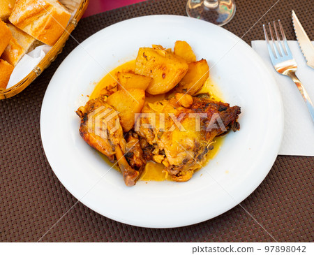 Braised chicken leg served with potato garnish Braised chicken leg served with potato garnish 97898042