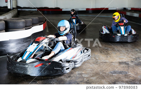 Group of people driving go-carts at racing track 97898083