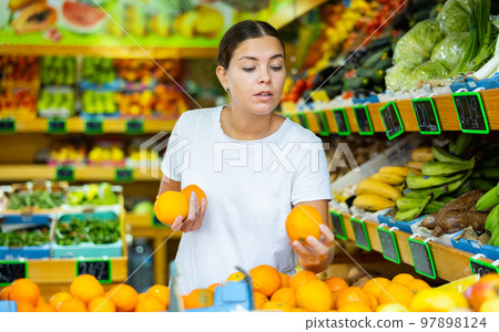 Portrait of young female choosing fresh oranges in store Portrait of young female choosing fresh oranges in store 97898124