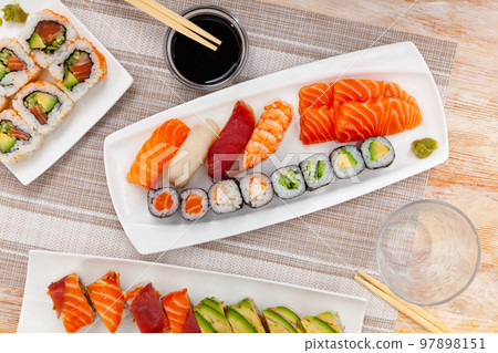 Assorted sushi rolls on plates on tabl 97898151