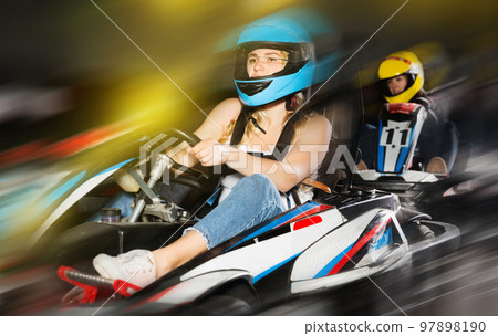 active woman in helmet driving car for karting with other people 97898190