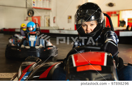 Female racer in helmet driving kart on track Female racer in helmet driving kart on track 97898296
