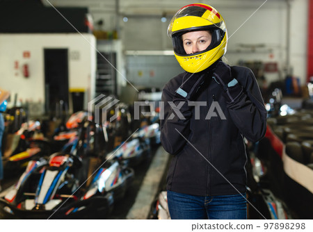 Girl in helmet posing near kart at track 97898298