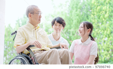 A helper who cares for an elderly person in a wheelchair 97898740