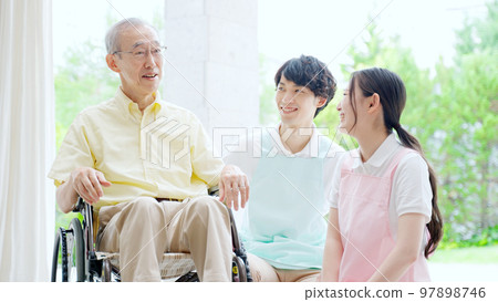 A helper who cares for an elderly person in a wheelchair A helper who cares for an elderly person in a wheelchair 97898746