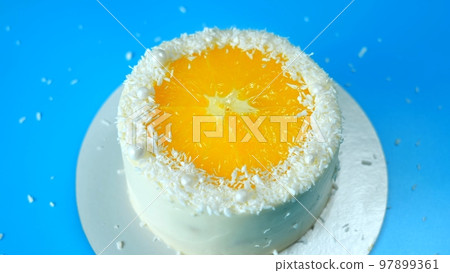 Cake with orange and coconut shavings spinning on a blue background. 97899361