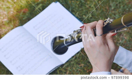 The girl plays the clarinet by notes. 97899398