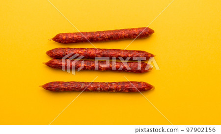 Flat lay of Spanish mini chorizo on yellow 97902156