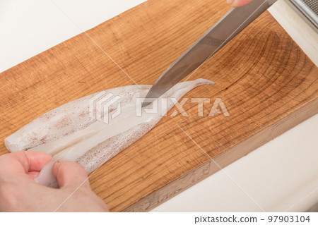 [A middle-aged housewife prepares a squid, cutting the body] 97903104