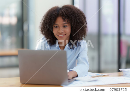 Young African American businesswoman working by laptop at office, Focus at screen laptop, reading interesting article online and finance Young African American businesswoman working by laptop at office, Focus at screen laptop, reading interesting article online and finance 97903725