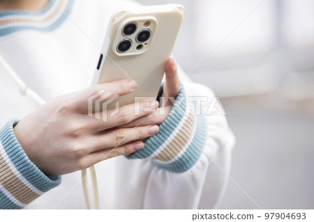 一個年輕女人的手在操作智能手機 97904693