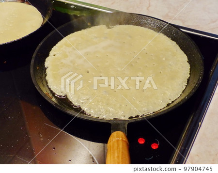 Cooking pancakes. Traditional russian blin on a cast-iron frying pan. Maslenitsa is an Eastern Slavic traditional holiday, celebrated during the week before the Great Lent. 97904745