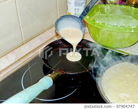 Cooking pancakes. Traditional russian blin on a cast-iron frying pan. Maslenitsa is an Eastern Slavic traditional holiday, celebrated during the week before the Great Lent. 97904747