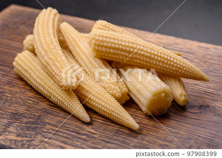 A bunch of small white canned corn on a dark concrete background 97908399