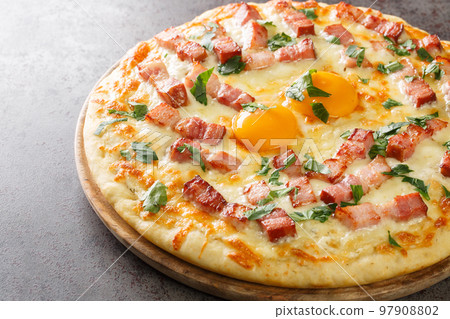 White pizza carbonara with egg, cream, bacon, cheese and herb closeup on the wooden board. Horizontal White pizza carbonara with egg, cream, bacon, cheese and herb closeup on the wooden board. Horizontal 97908802