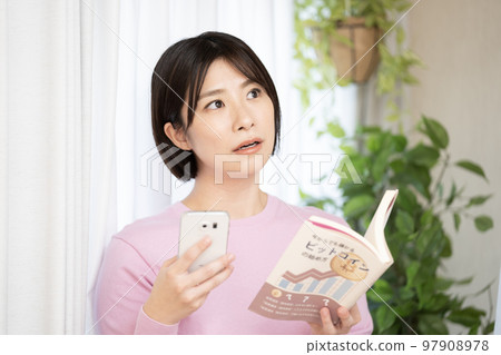Woman with investment book and smartphone Woman with investment book and smartphone 97908978